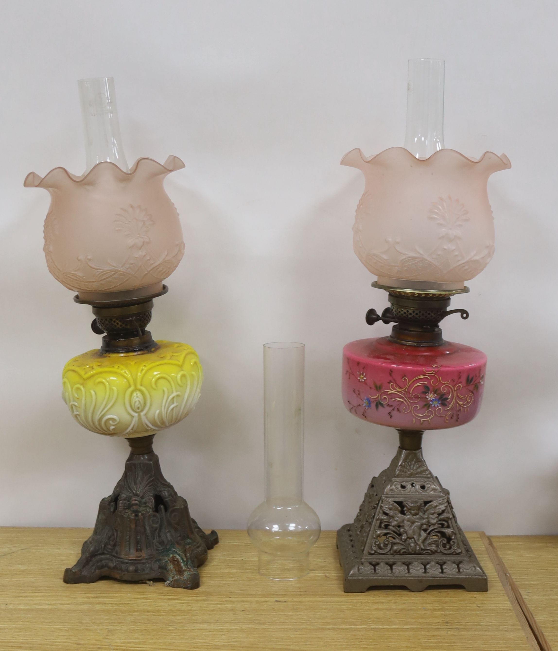 Two late Victorian brass mounted oil lamps with pink and yellow tinted glass reservoirs, tallest 61 cm